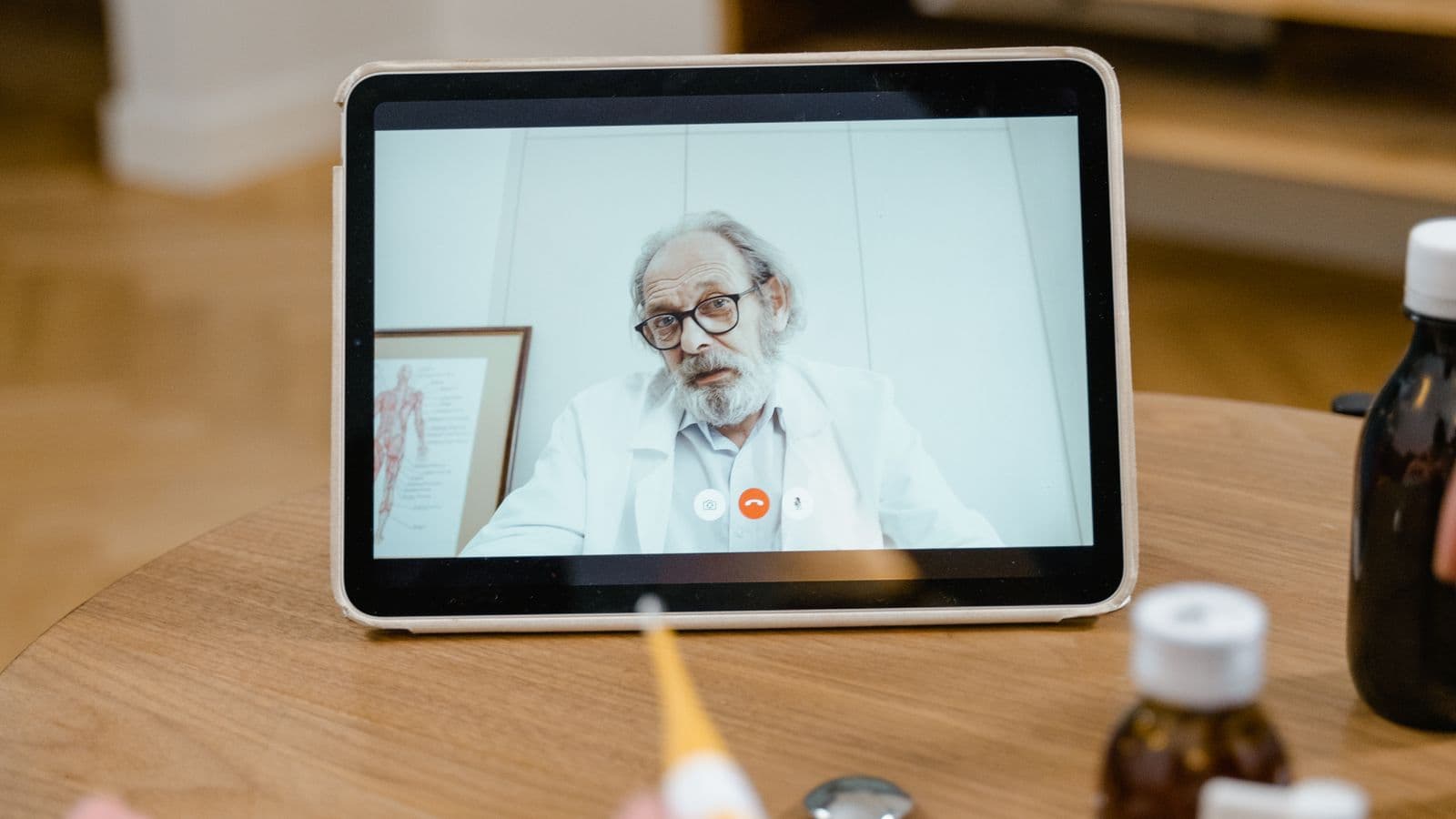 Tablet exibindo consulta médica por vídeo, com frascos de medicamento ao lado