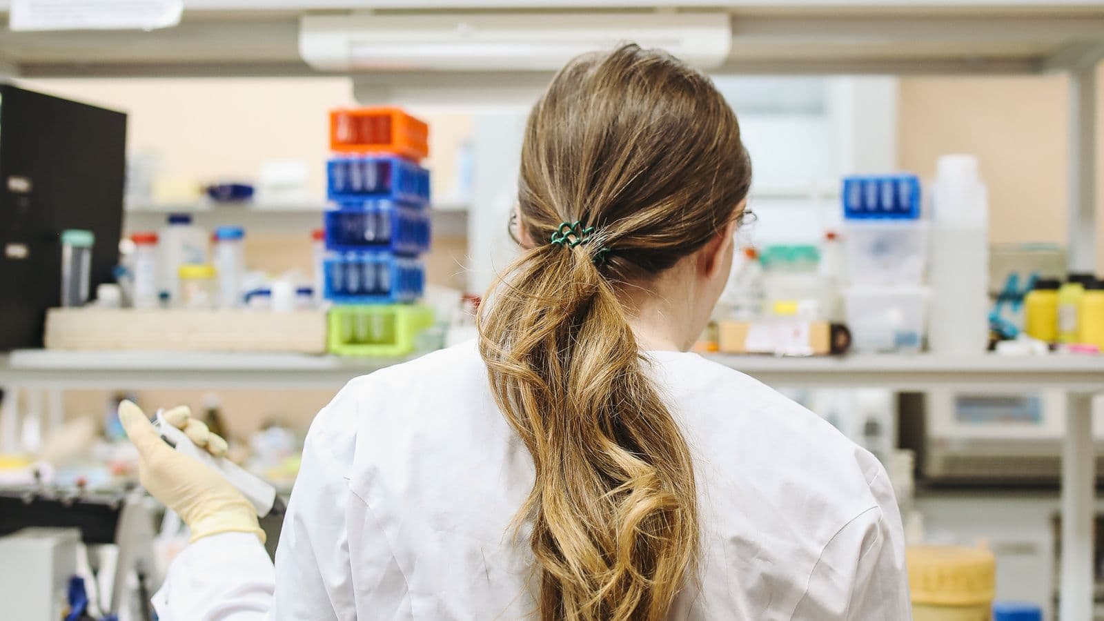 Pesquisadora de jaleco trabalhando em bancada de laboratório