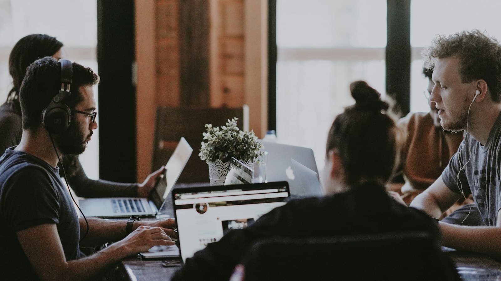 Young people working side by side on laptops at a shared table